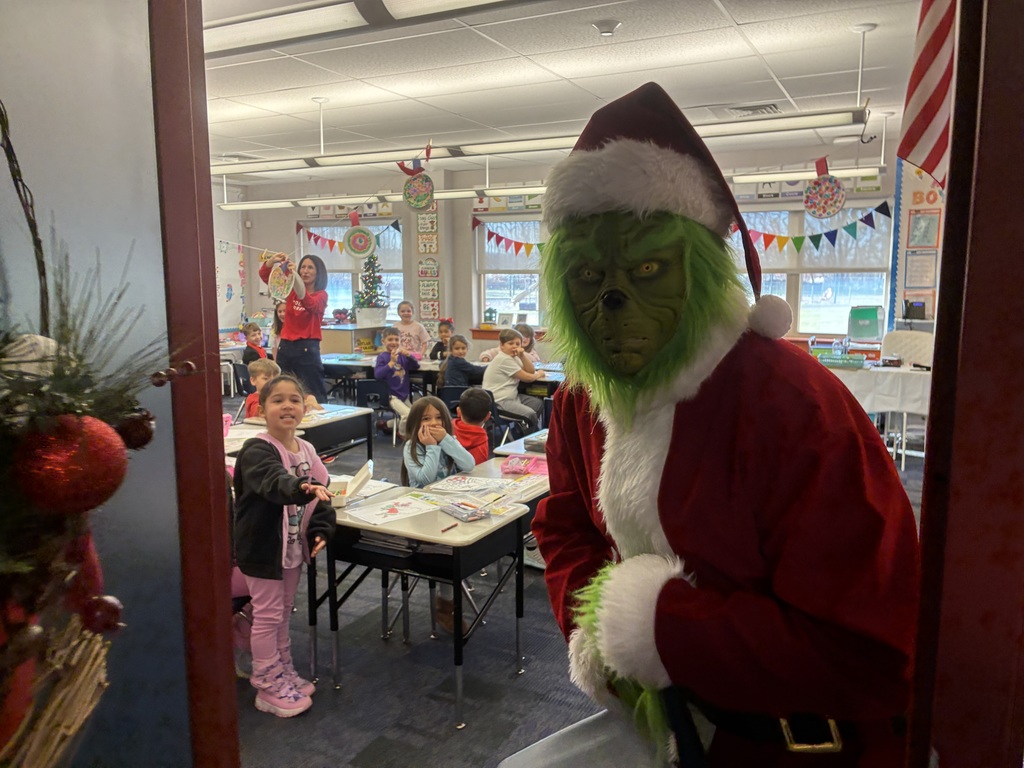 A man in a grinch costume in a school. 