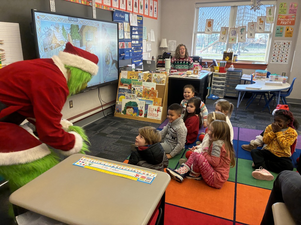 A man in a grinch costume in a school. 