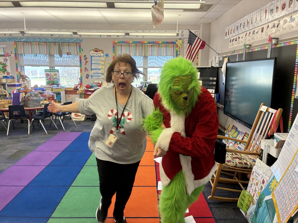 A man in a grinch costume in a school. 