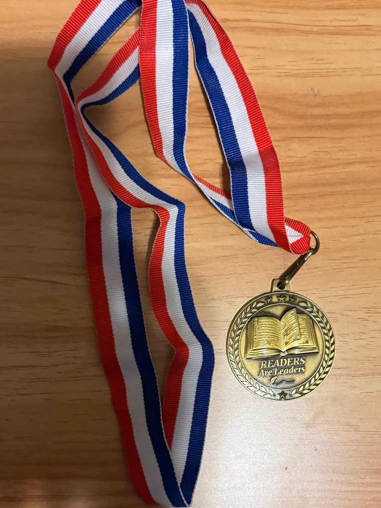 Students in a assembly in the gym with a slide projected with top readers.  