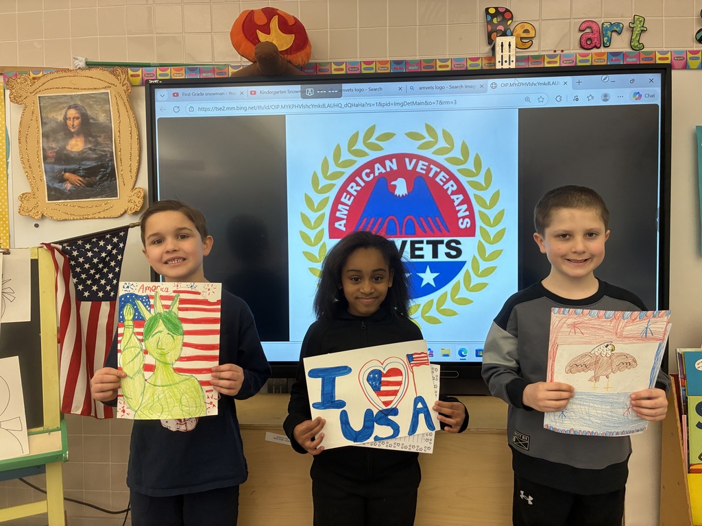 Students holding patriotic drawings in front of a smart board with the AMVETs logo. 