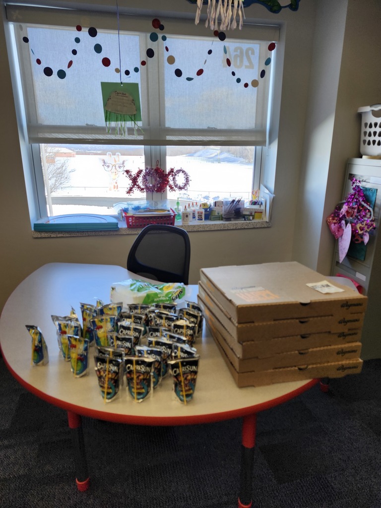 Boxes of pizza and caprisuns on a classroom table,