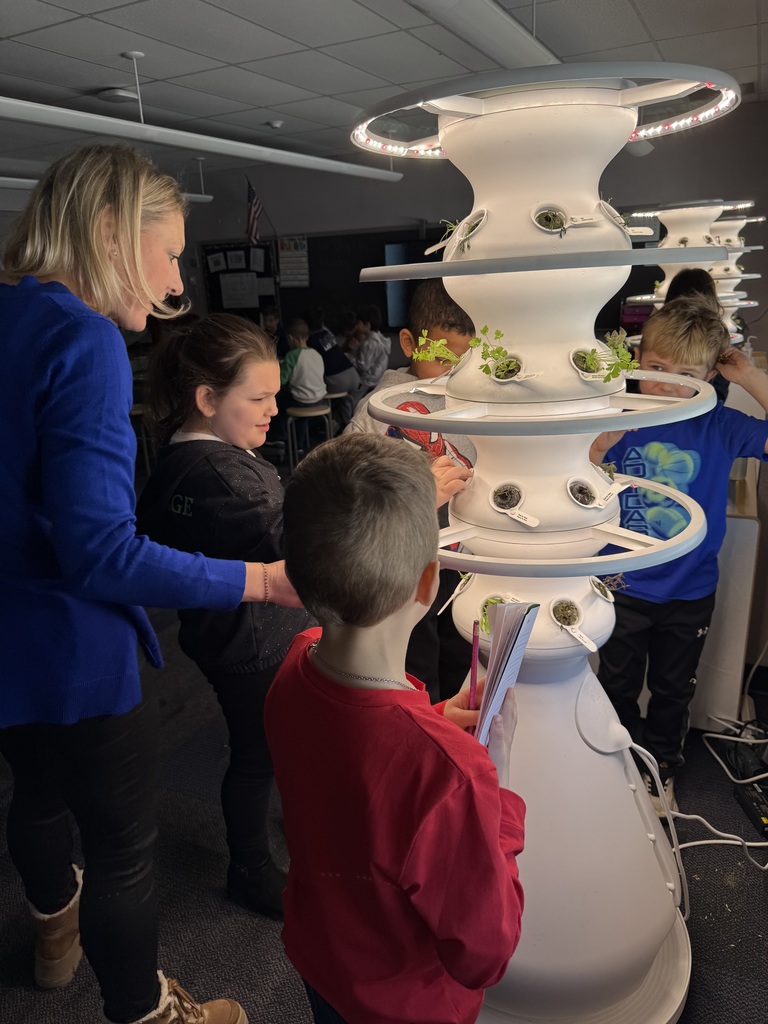 Students and a teacher planting seedlings in a white hydroponic farm stand.