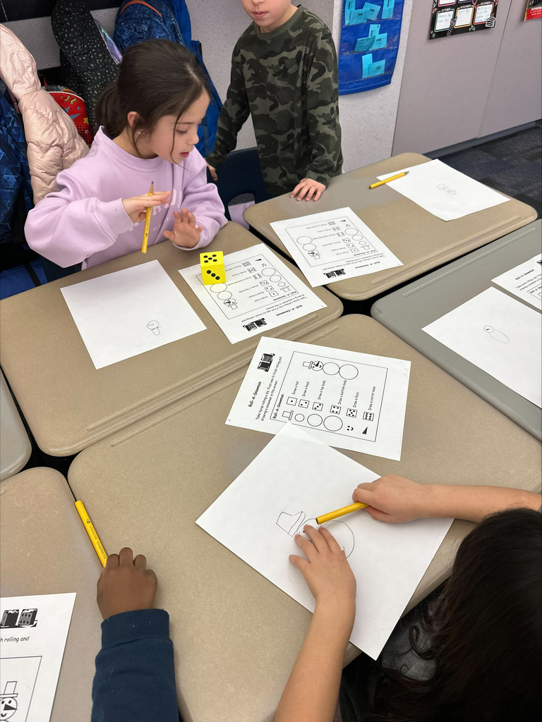 Students with a large dice and activity sheets at their desks.