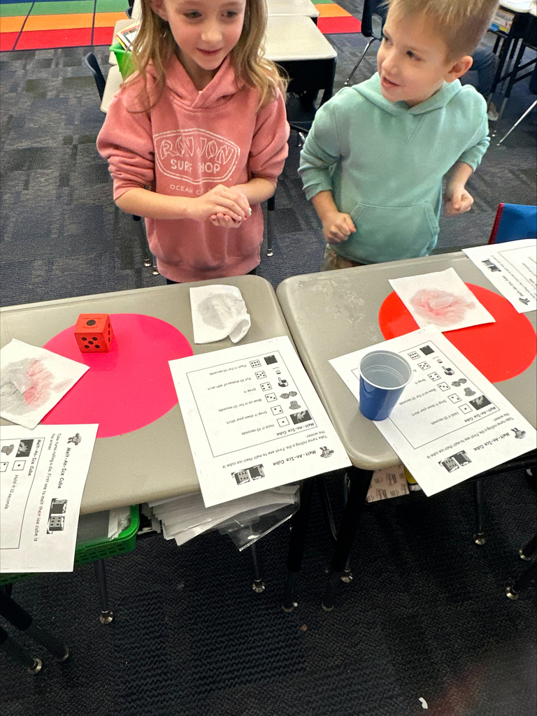 Students with a large dice and activity sheets at their desks.