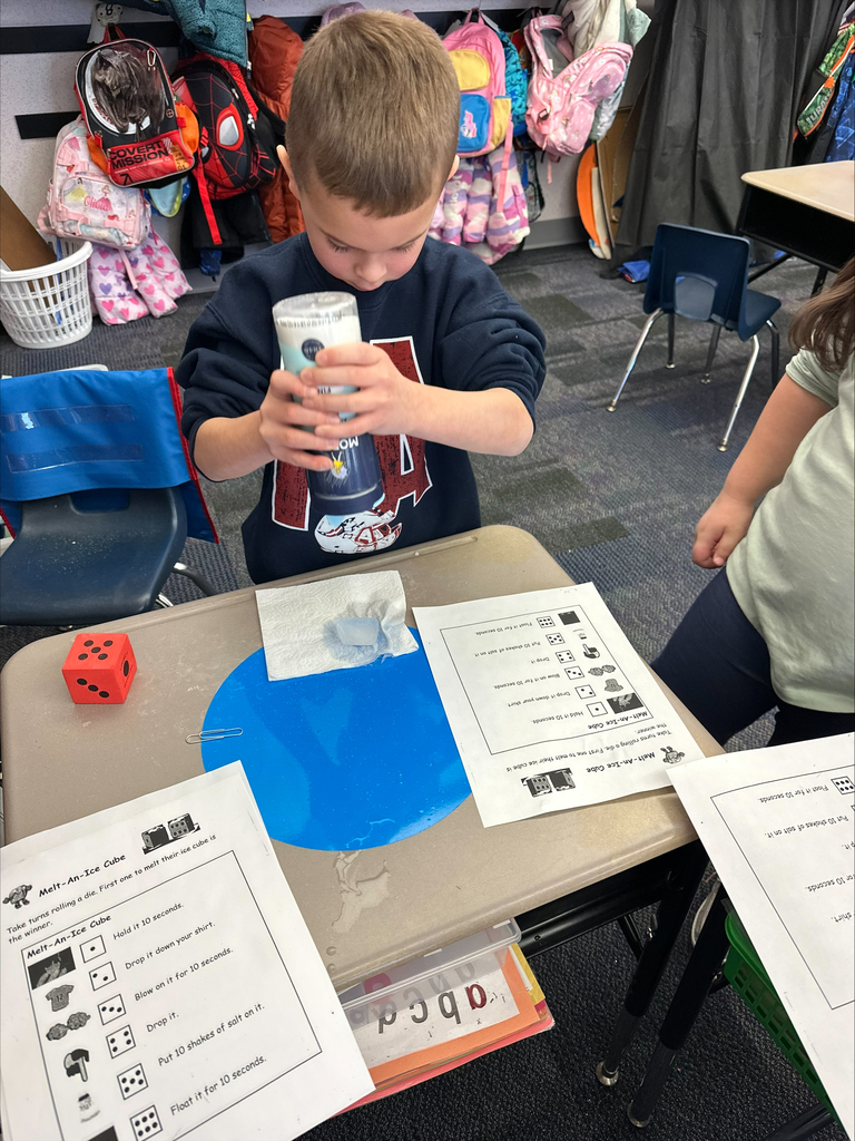 Students with a large dice and activity sheets at their desks.