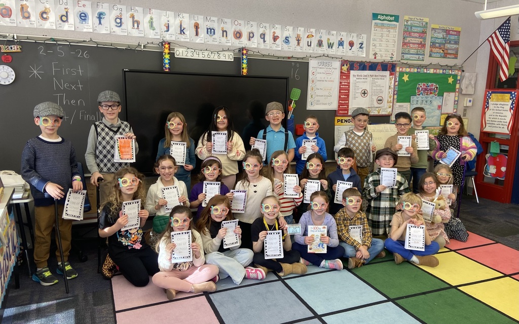 A group of children wearing 100 glasses and holding 100 books.