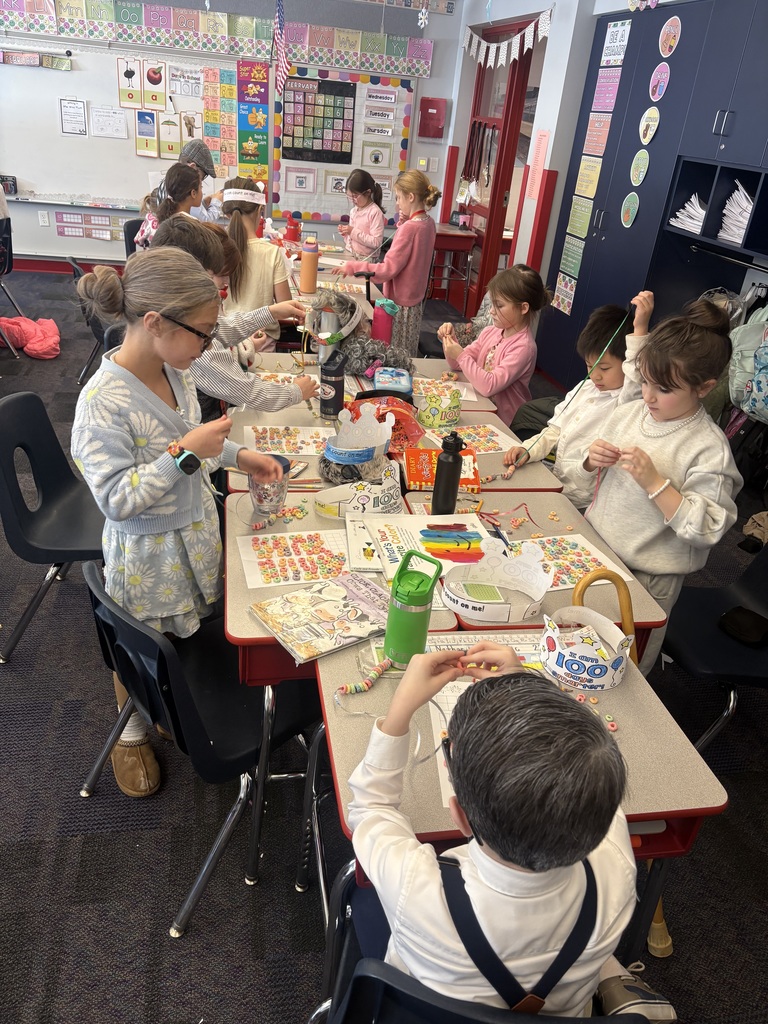 Students at their desks stringing 100 fruit loop necklaces.
