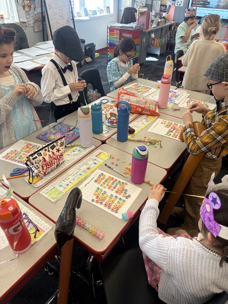 Students at their desks stringing 100 fruit loop necklaces.