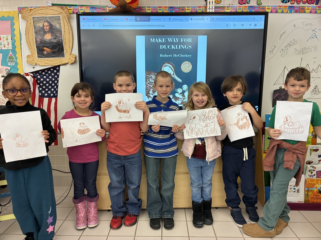 Students holding brown duck drawings. 
