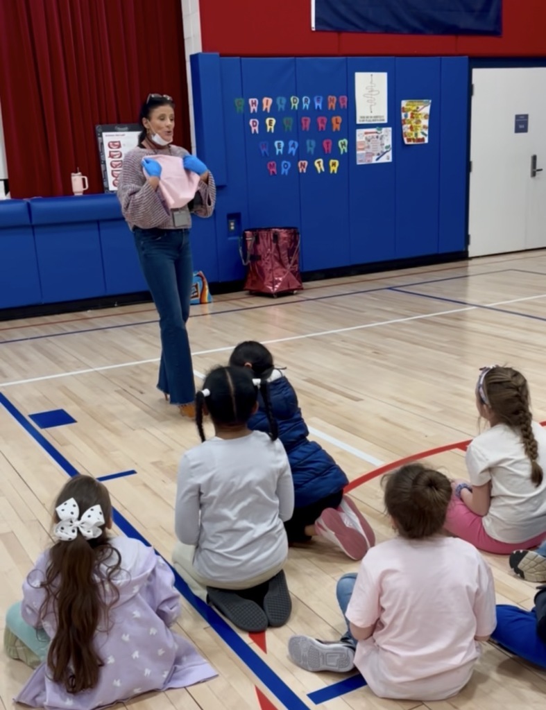 Mrs. Baumes presenting to students seated in the gym