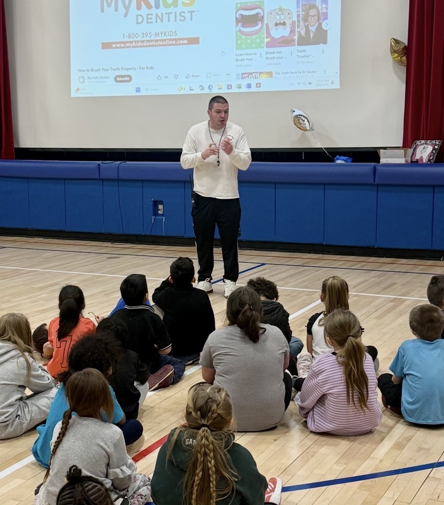 Mr. McDermott presenting to students seated in the gym.