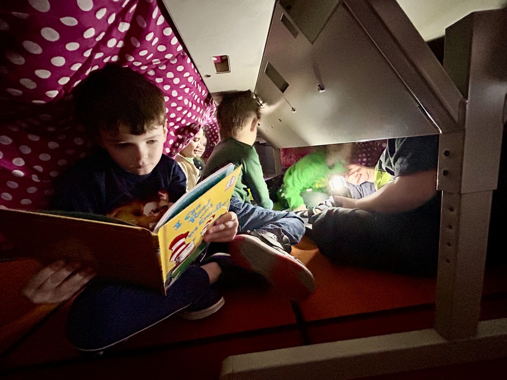 A blanket tent in a classroom with students reading books