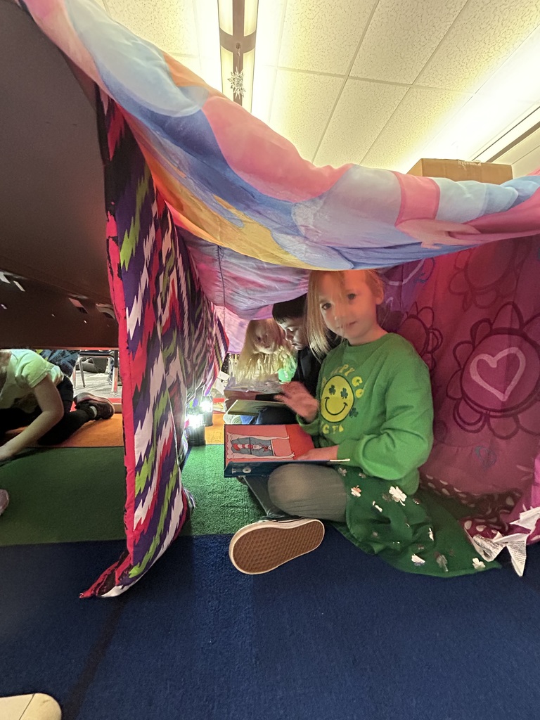 A blanket tent in a classroom with students reading books