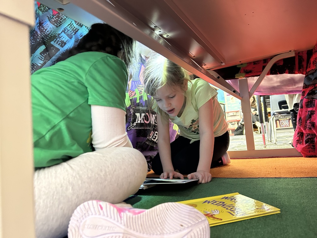 A blanket tent in a classroom with students reading books