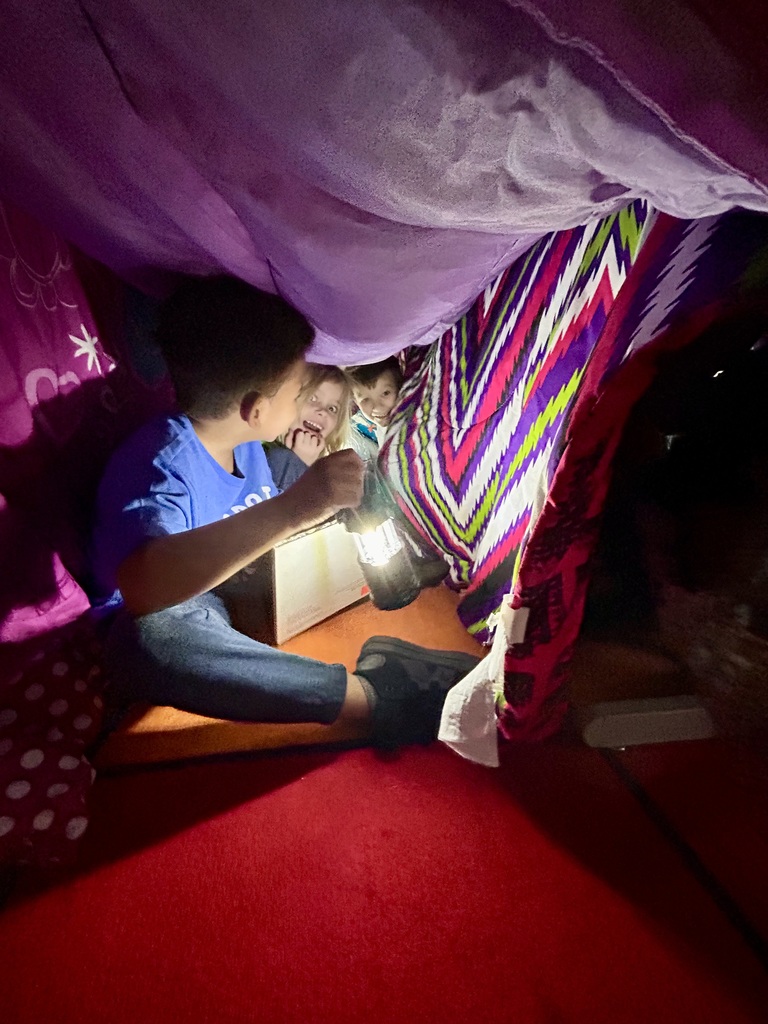 A blanket tent in a classroom with students reading books