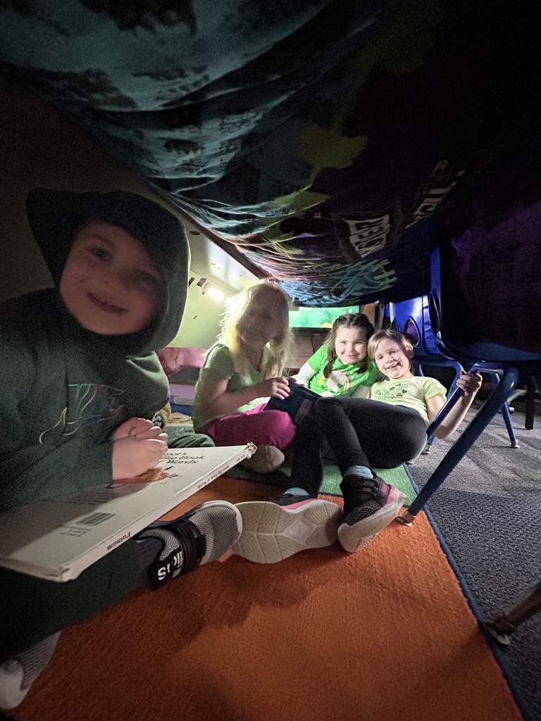 A blanket tent in a classroom with students reading books