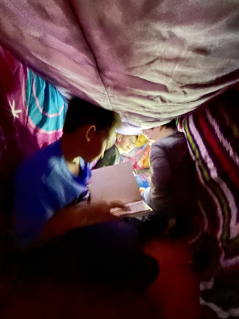 A blanket tent in a classroom with students reading books