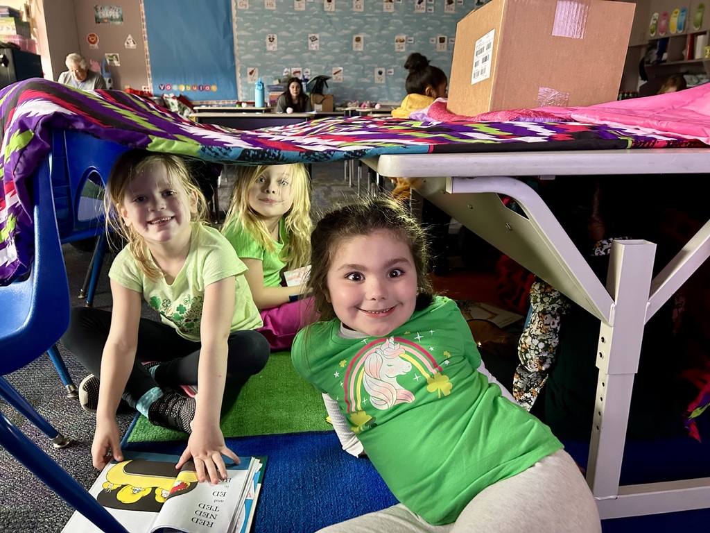 A blanket tent in a classroom with students reading books