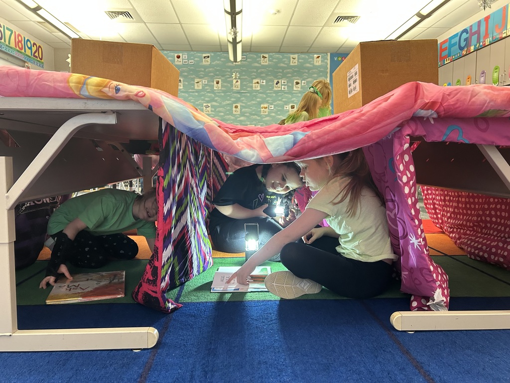 A blanket tent in a classroom with students reading books
