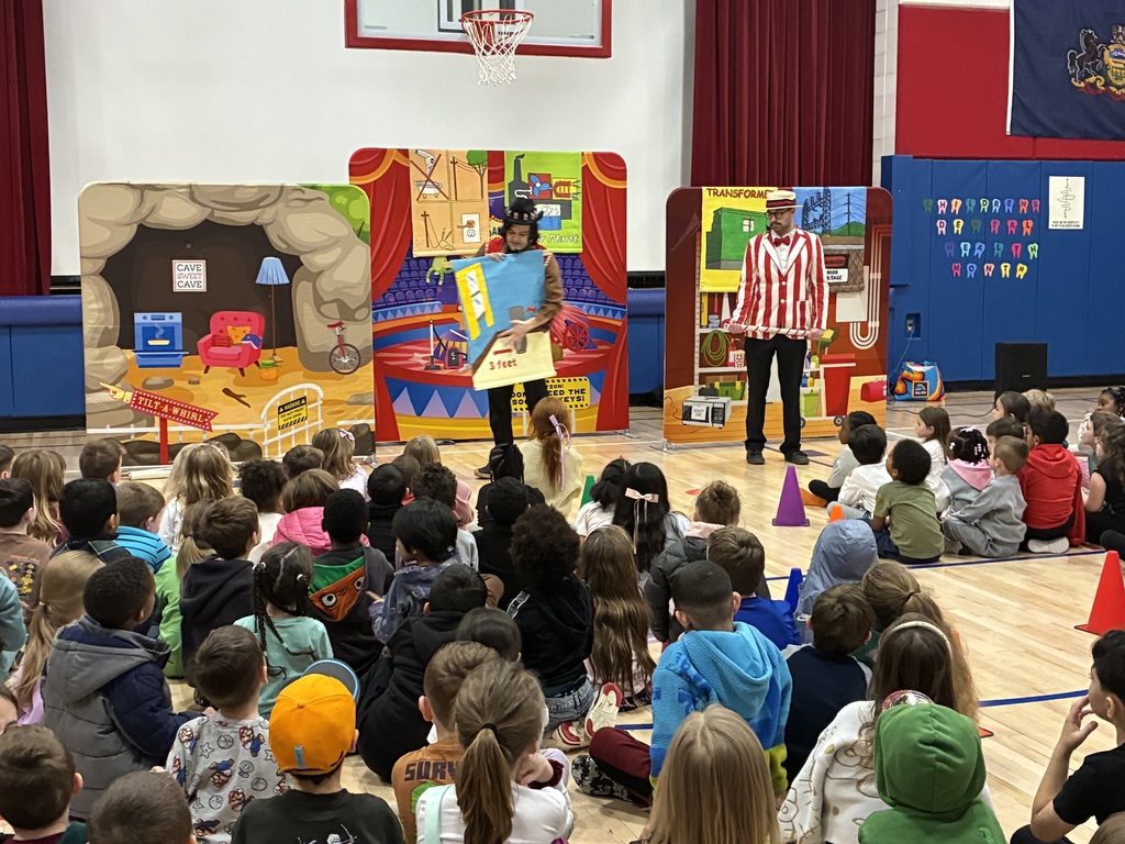 A group of students seated at an assembly in the gym with the backdrop PPL