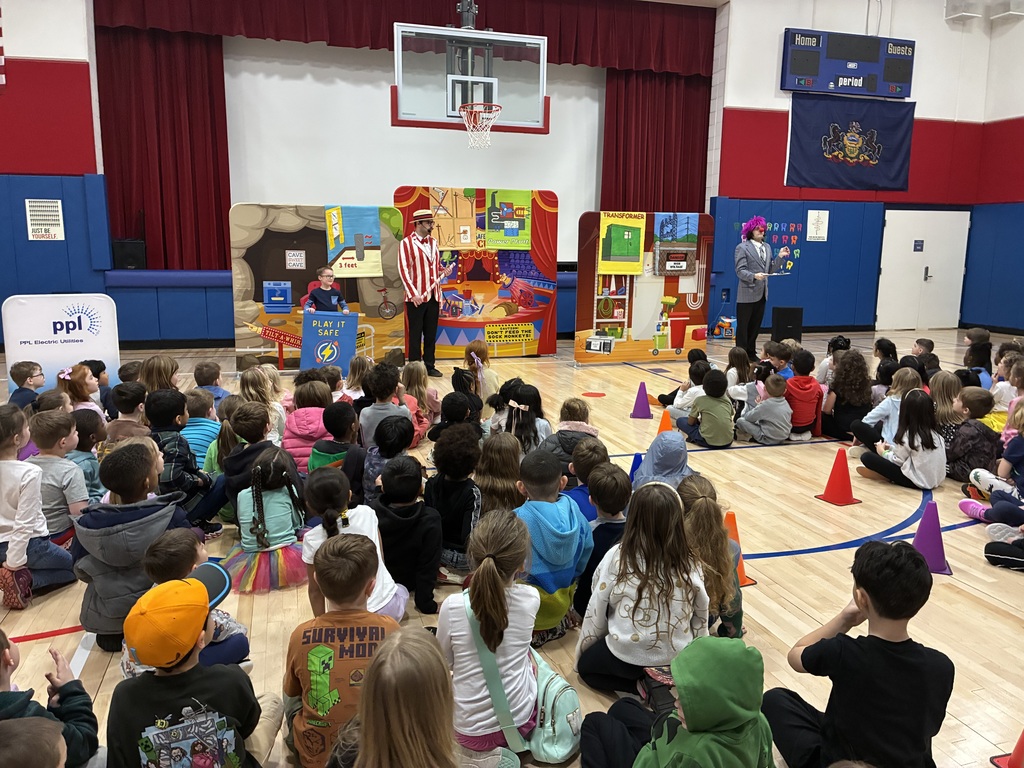 A group of students seated at an assembly in the gym with the backdrop PPL