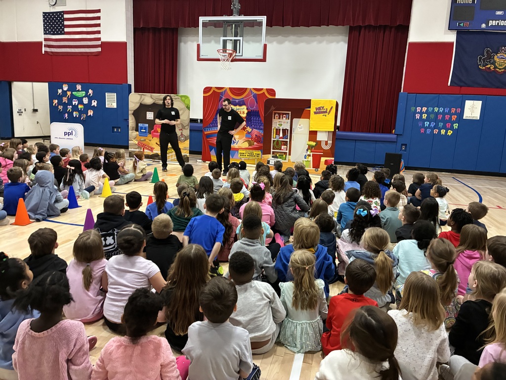 A group of students seated at an assembly in the gym with the backdrop PPL