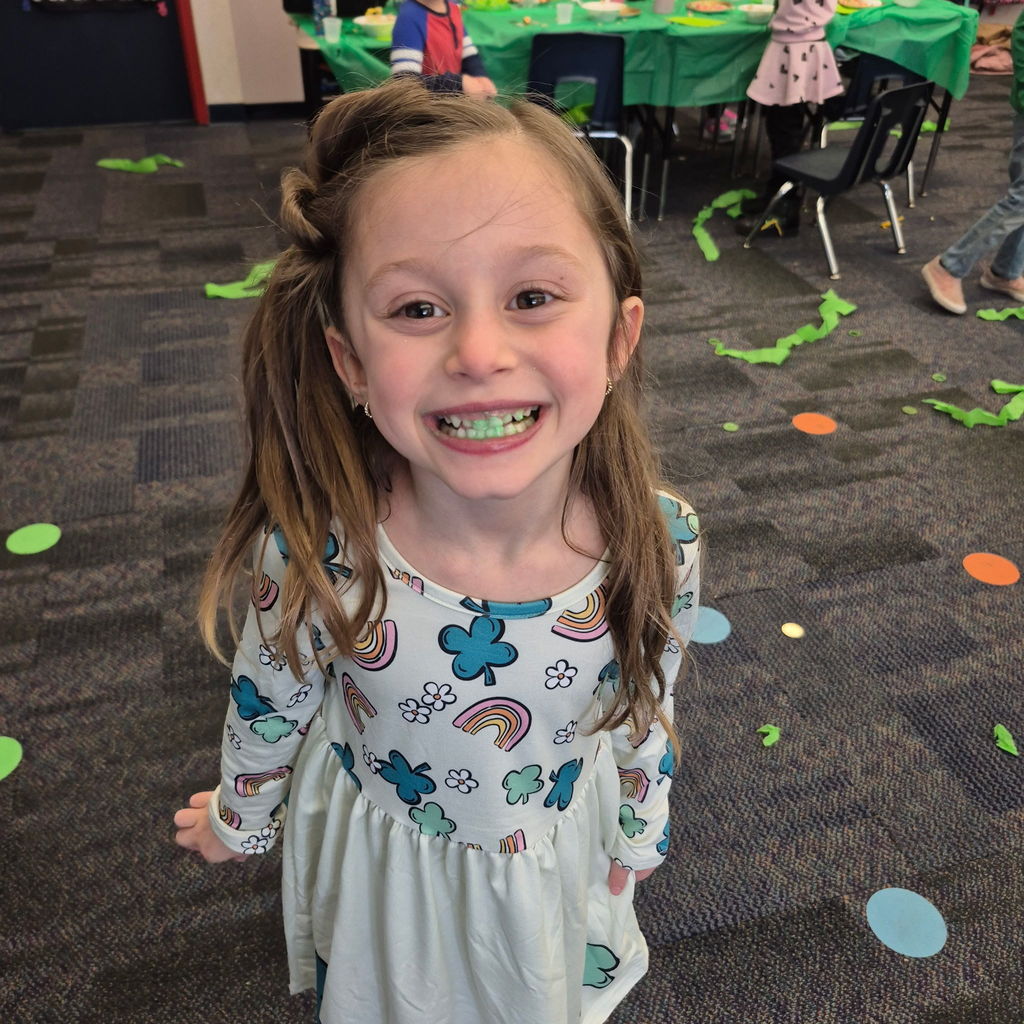 A girls smiling with green teeth.