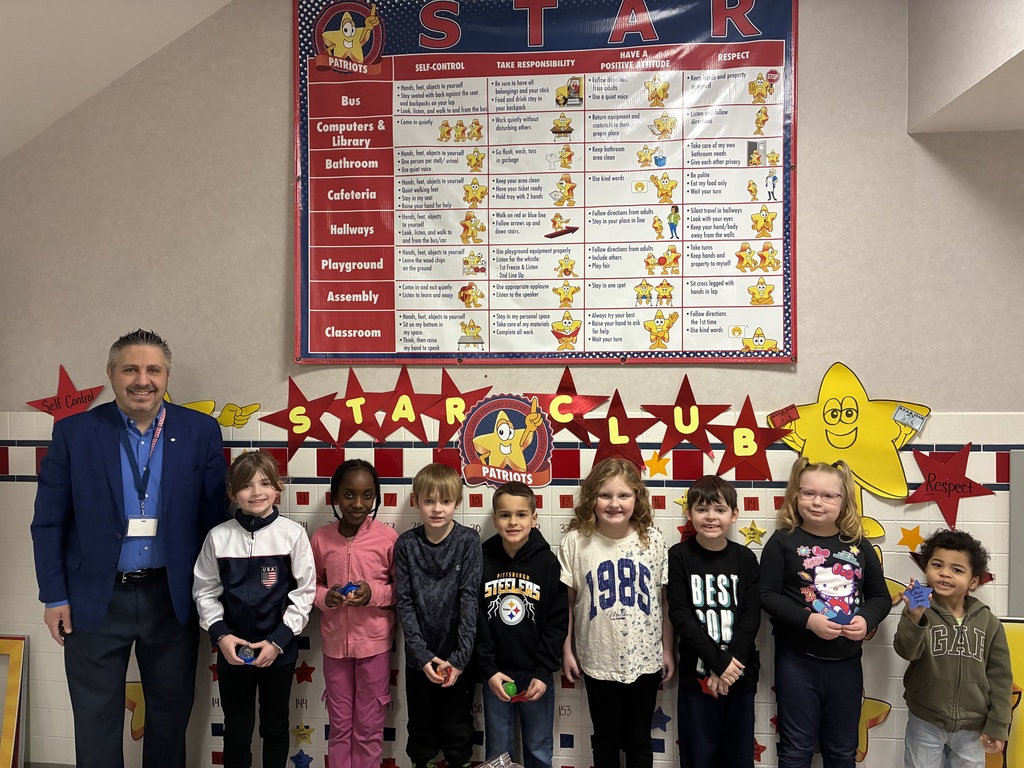Students in front of the star club board smiling with prizes.