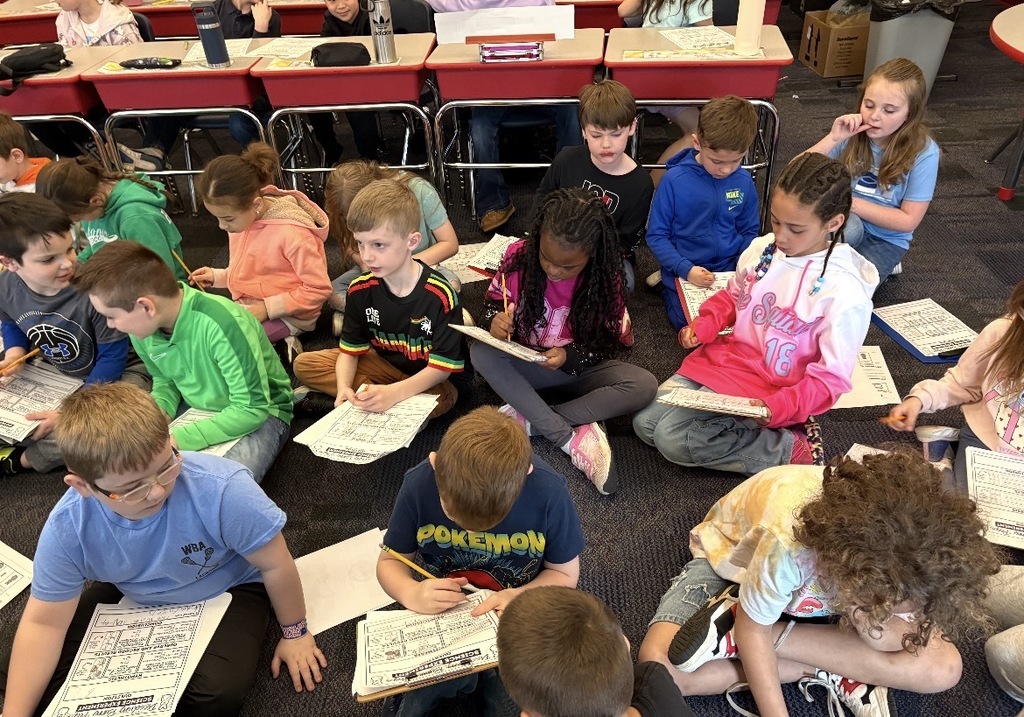 Students seated with clipboards observing blue marshmallow peeps in different liquids  
