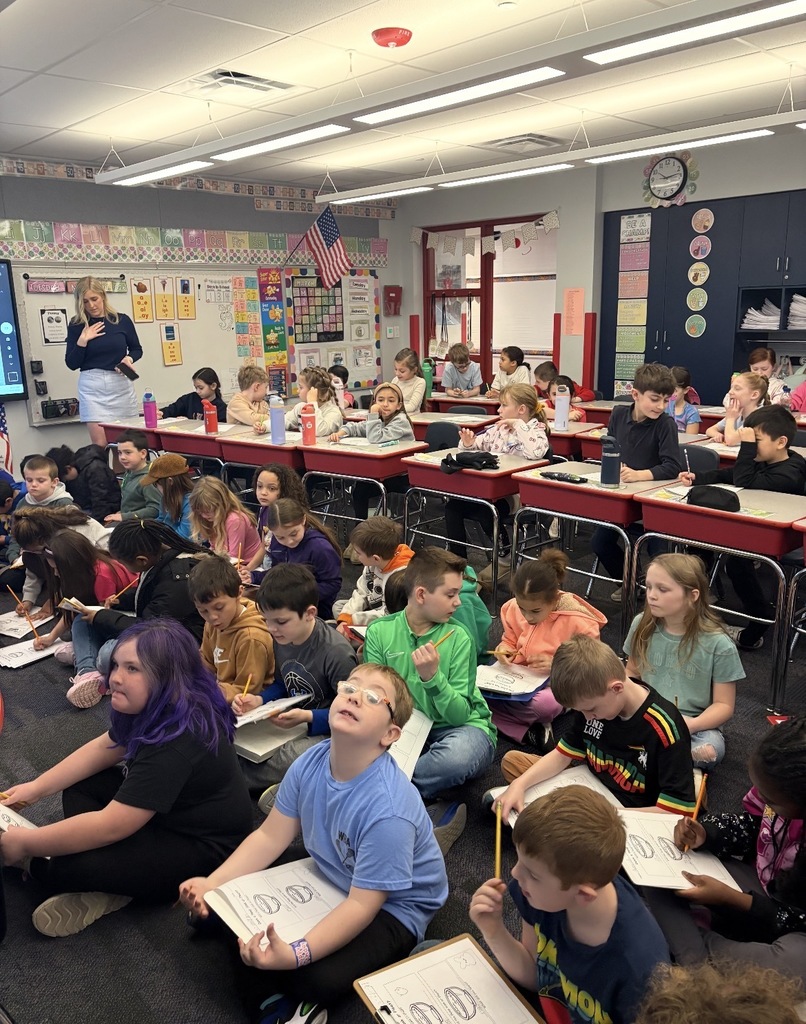 Students seated with clipboards observing blue marshmallow peeps in different liquids  