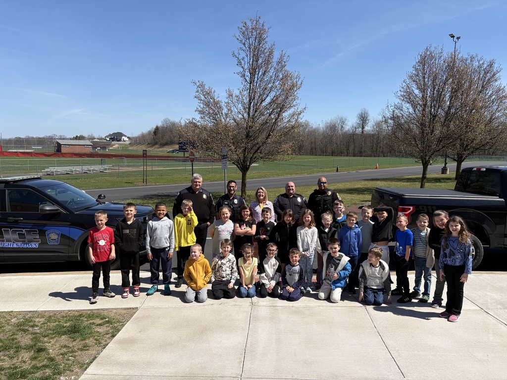 A group of students posing with a teacher and 4 uniformed police officers  