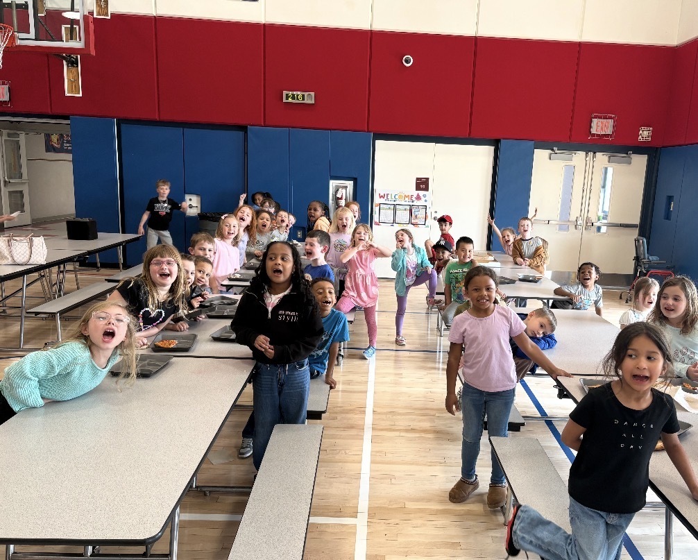 Students seated in a cafeteria eating pizza