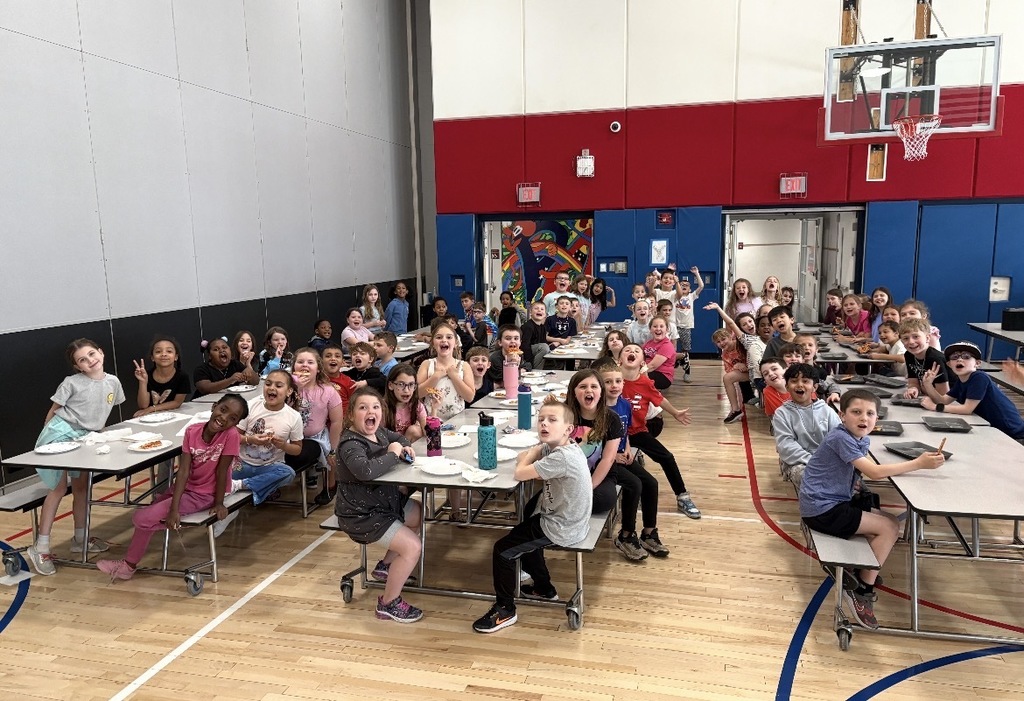 Students seated in a cafeteria eating pizza