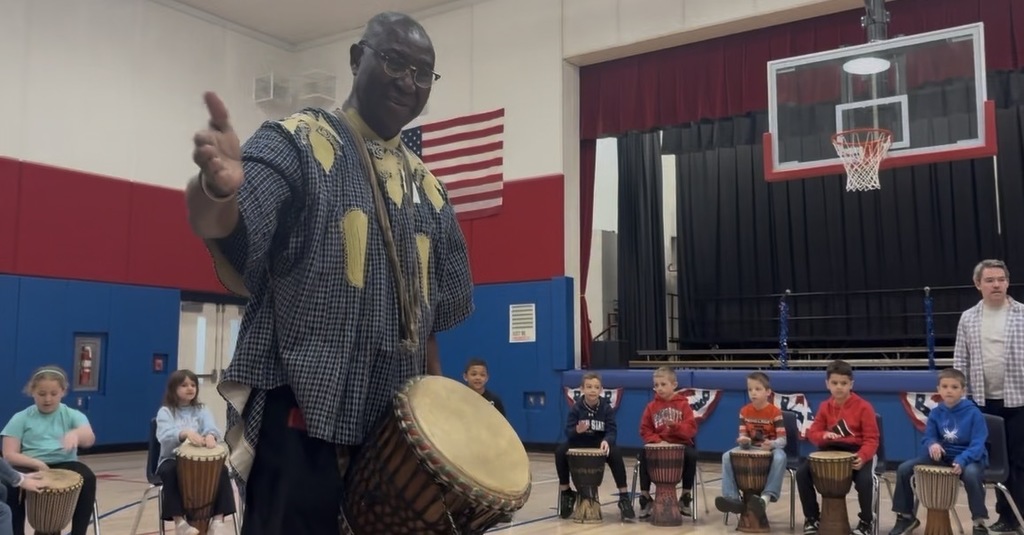 African drummer with students in a gym with drums. 