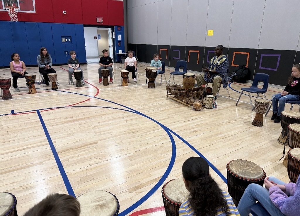 African drummer with students in a gym with drums. 