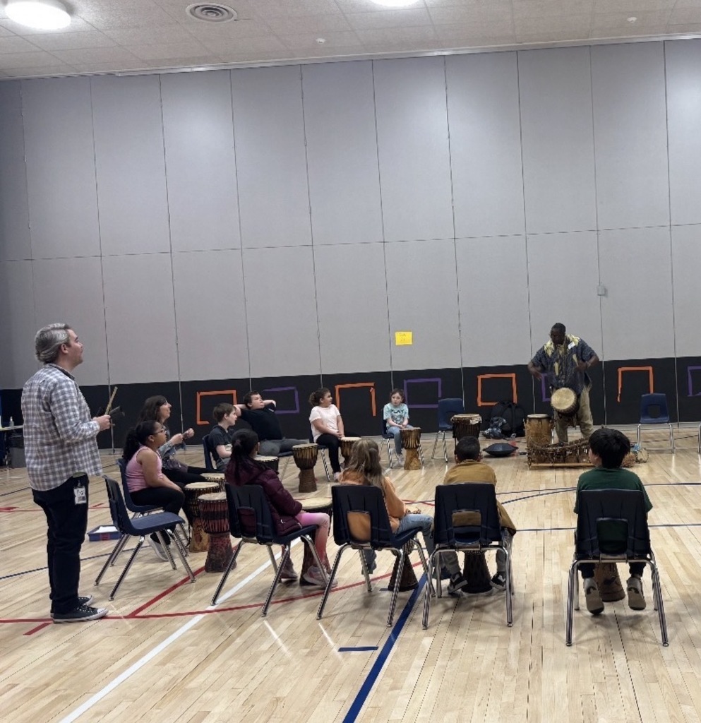 African drummer with students in a gym with drums. 