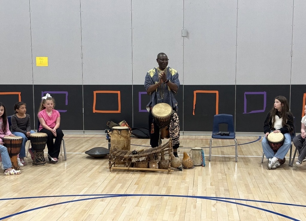 African drummer with students in a gym with drums. 