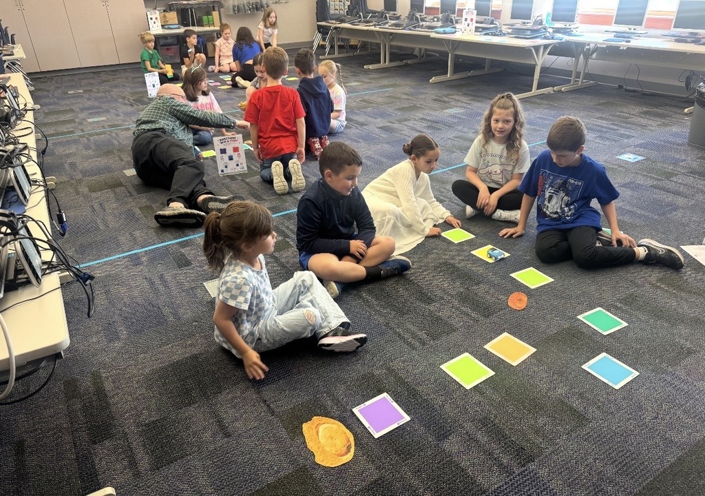 Students coding car robots with squares 