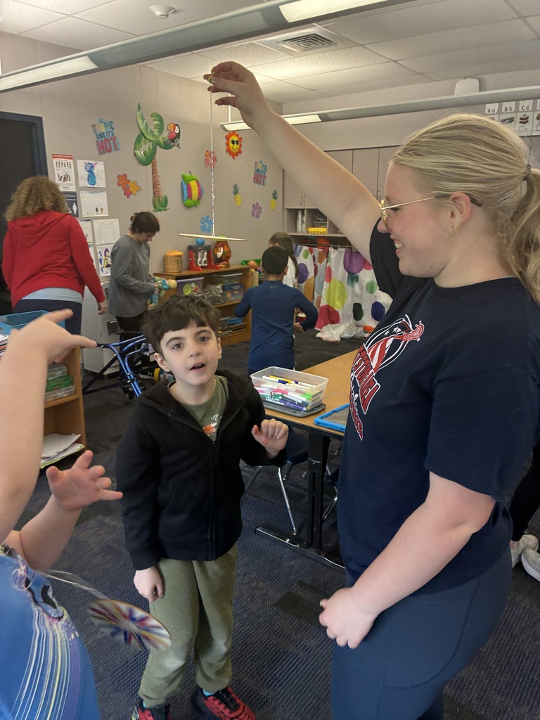 Kindergarten students coloring a spinner with a high school student. 