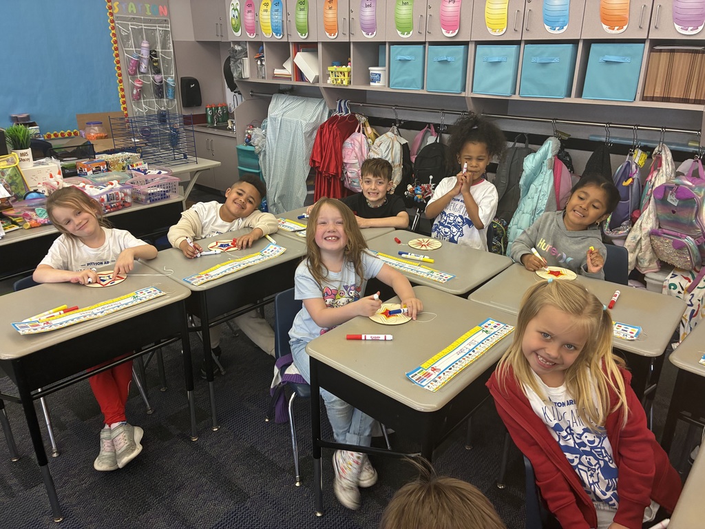 Kindergarten students coloring a spinner with a high school student. 