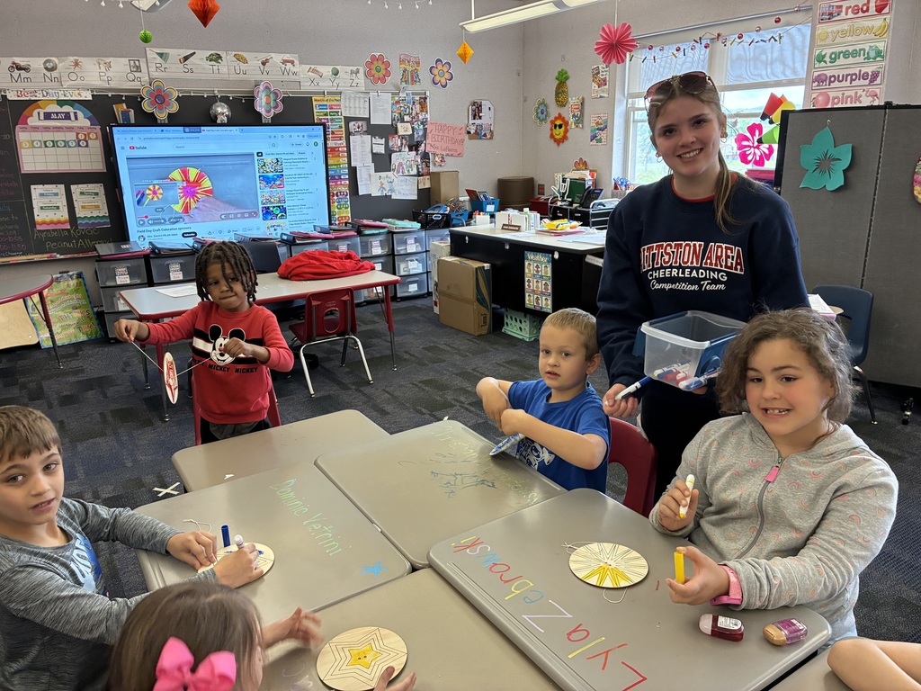 Kindergarten students coloring a spinner with a high school student. 