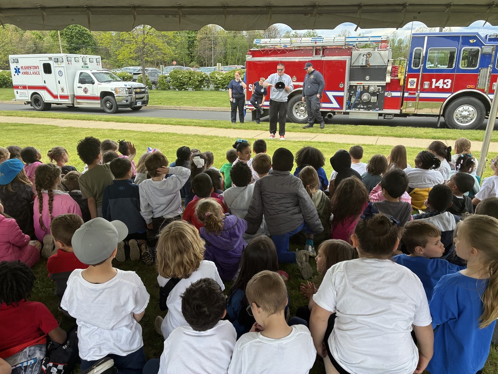 Students seated outside looking at an ambulance and fire truck