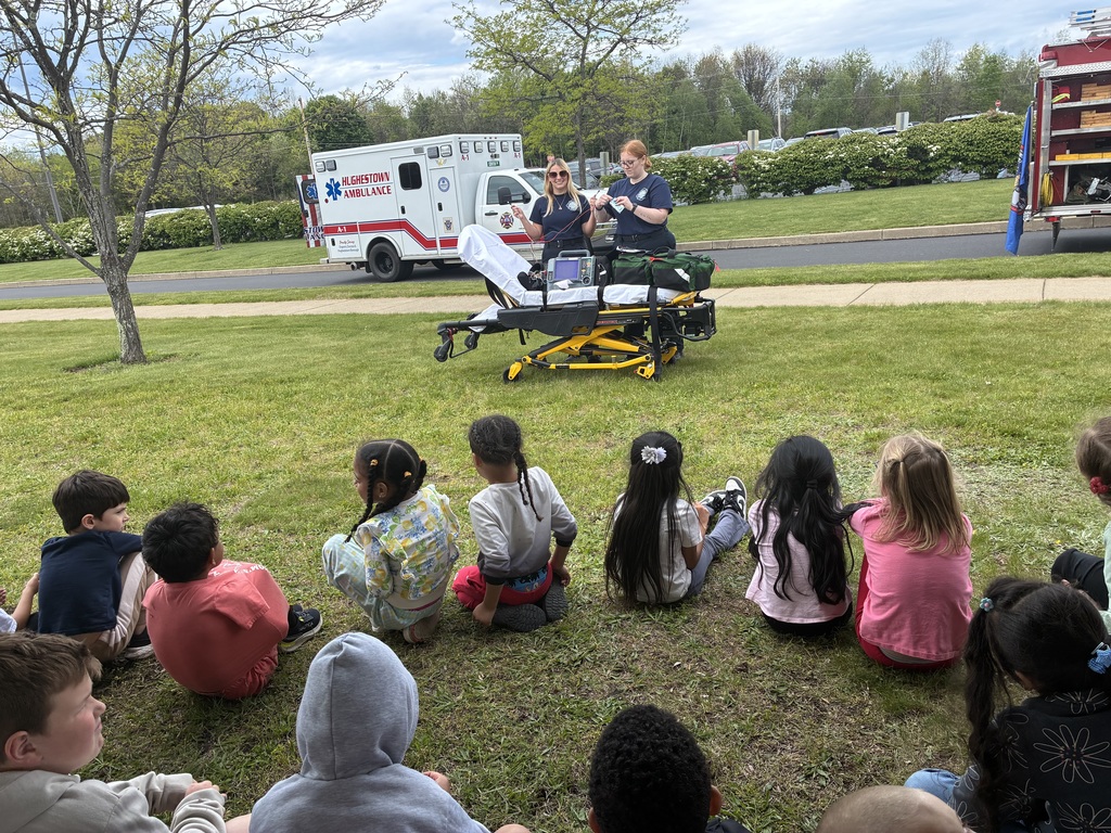 Students seated outside looking at an ambulance and fire truck