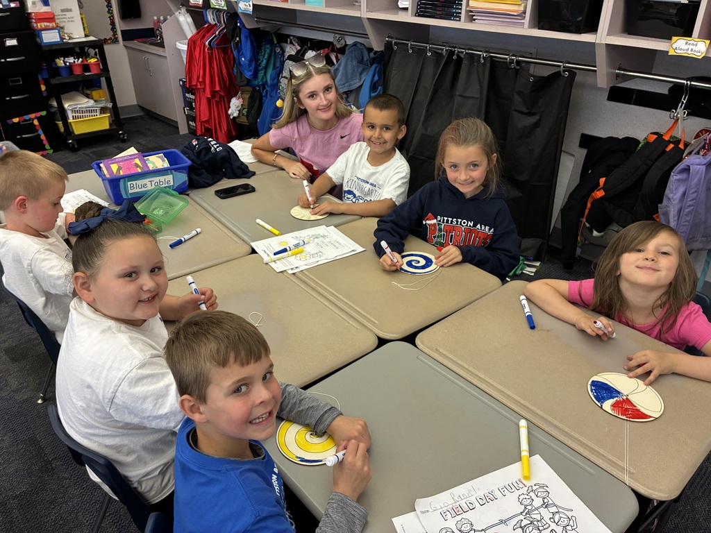 Kindergarten students coloring a spinner with a high school student. 