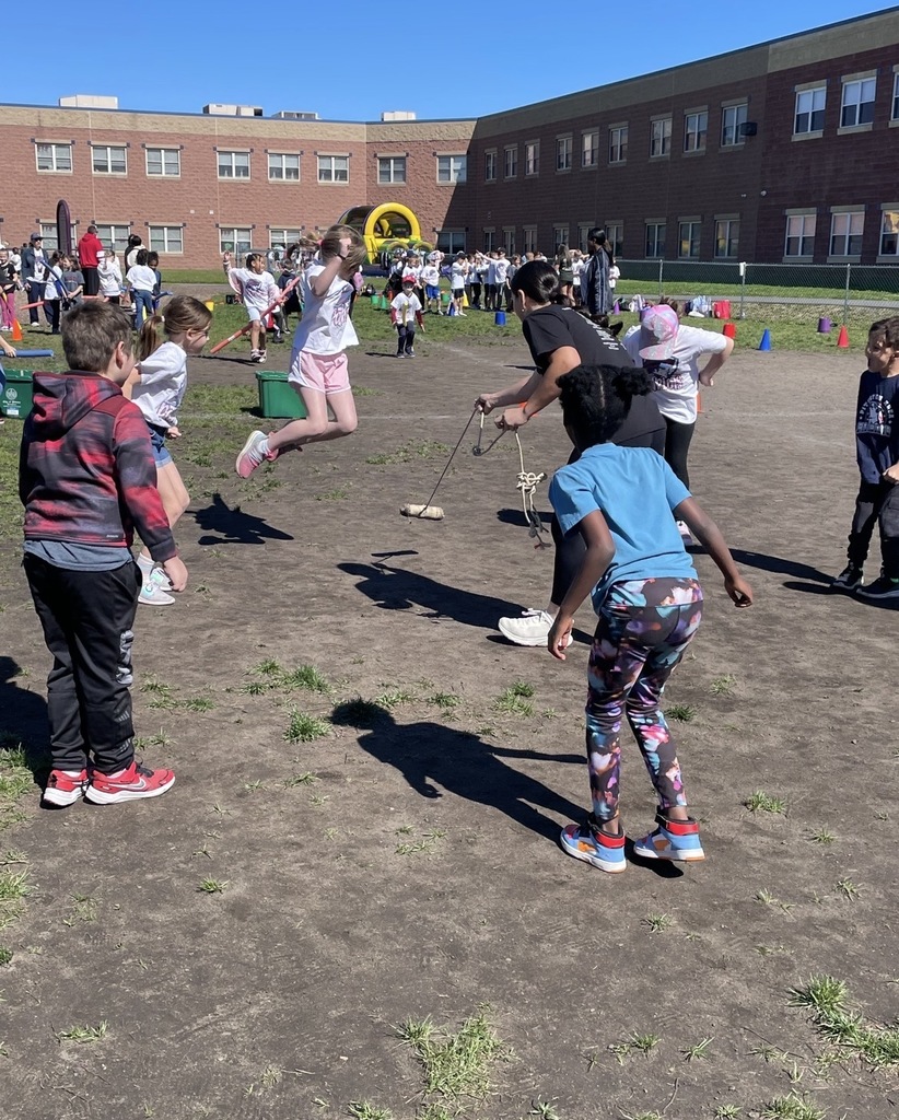 Students at field day in a circle jumping a rope 