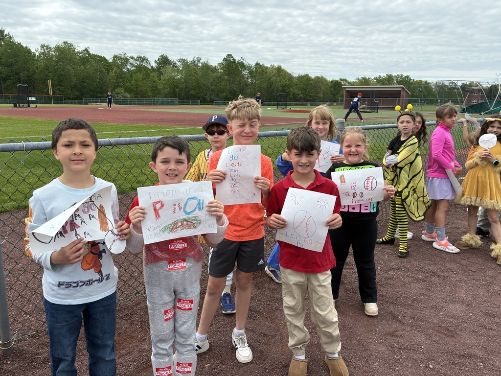Primary students and varsity baseball players outside the baseball field 