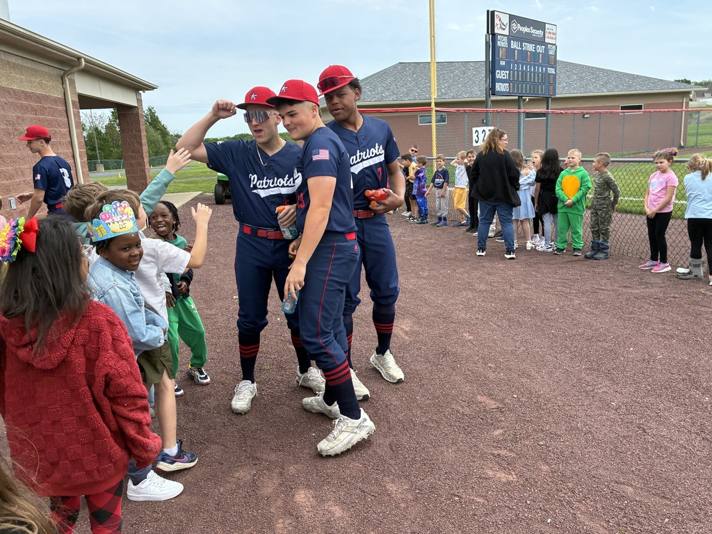 Primary students and varsity baseball players outside the baseball field 