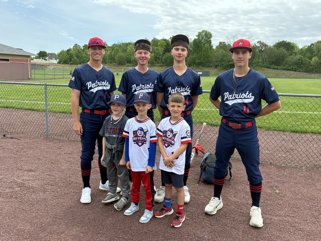 Primary students and varsity baseball players outside the baseball field 