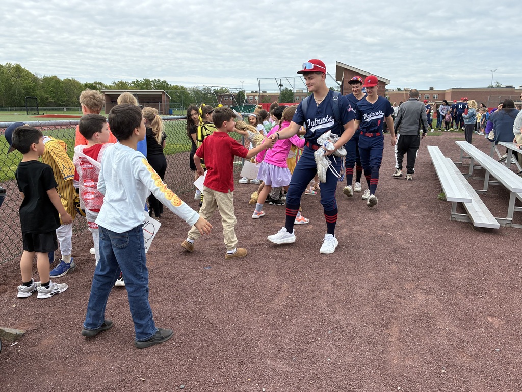 Primary students and varsity baseball players outside the baseball field 